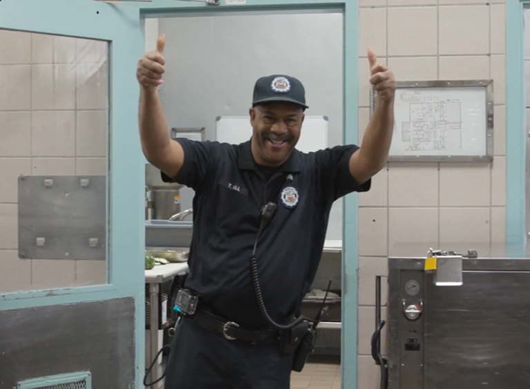 Male correctional officer giving two thumbs up and smiling